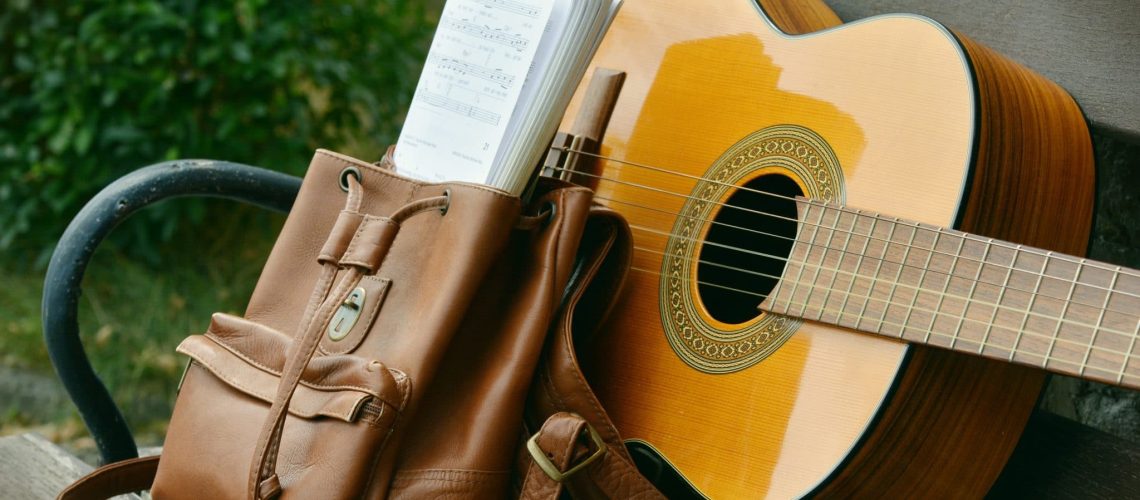 brown-acoustic-guitar-beside-brown-leather-bucket-backpack-164697